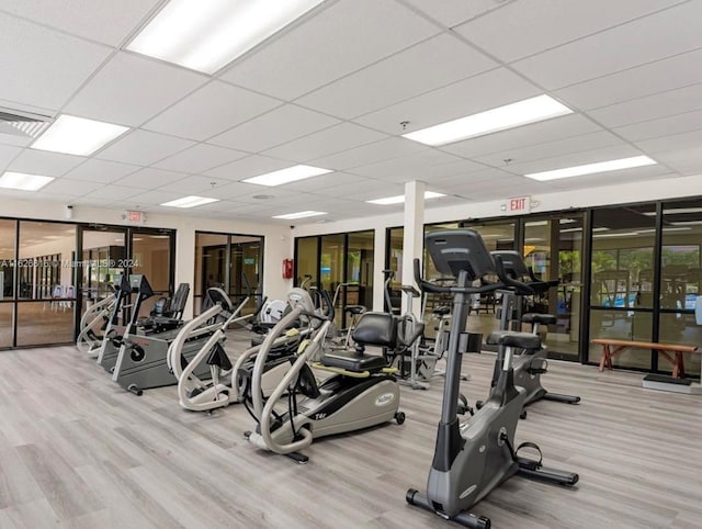 gym with light hardwood / wood-style floors and a paneled ceiling