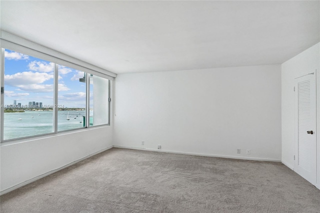 unfurnished room with light carpet and a water view