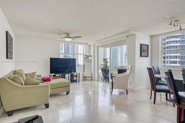 living room featuring ceiling fan and a textured ceiling