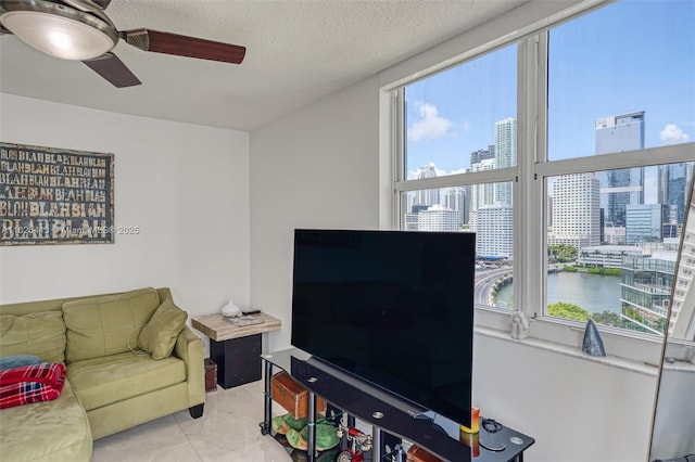 tiled living room featuring ceiling fan, a textured ceiling, and a healthy amount of sunlight