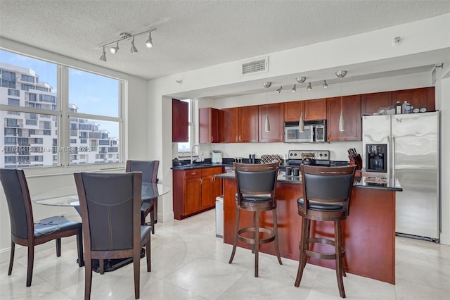 kitchen featuring appliances with stainless steel finishes, sink, a textured ceiling, and a center island