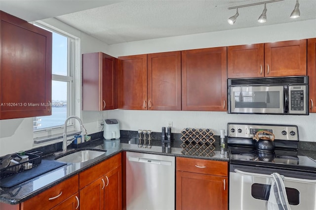 kitchen with appliances with stainless steel finishes, sink, plenty of natural light, and a textured ceiling