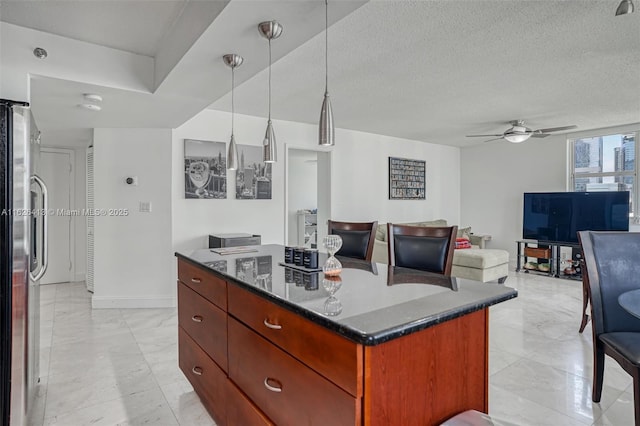 kitchen with hanging light fixtures, a textured ceiling, dark stone counters, stainless steel refrigerator, and a center island