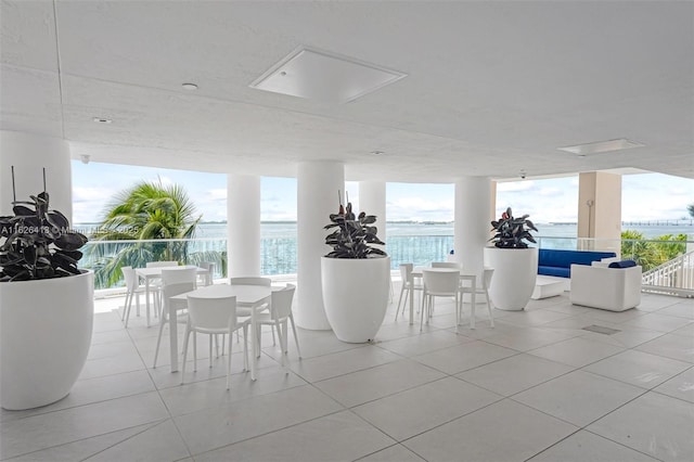 tiled dining space featuring a wall of windows and a water view