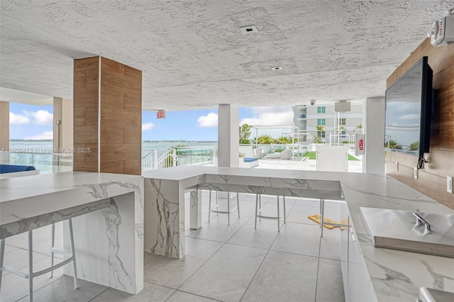 kitchen featuring a water view, light tile patterned floors, and light stone counters