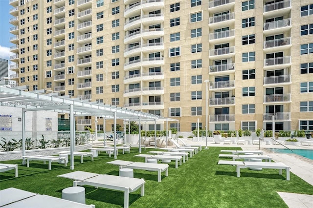 view of home's community with a pergola, a pool, and a lawn