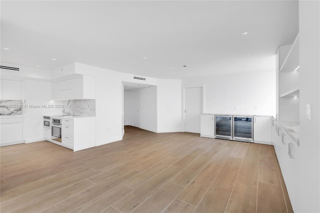 unfurnished living room with beverage cooler and light wood-type flooring