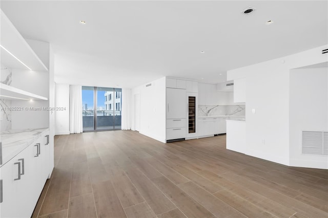 unfurnished living room with light wood-type flooring and a wall of windows