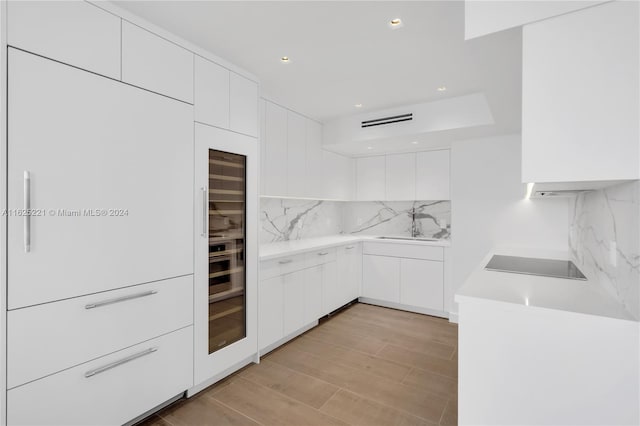 kitchen with white cabinetry, decorative backsplash, and light wood-type flooring