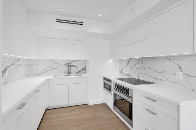 kitchen featuring sink, oven, decorative backsplash, white cabinetry, and black electric stovetop