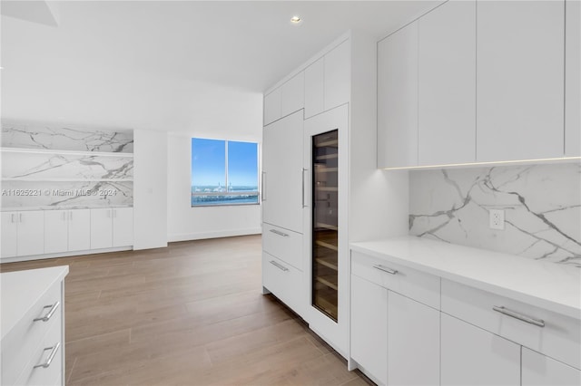 kitchen with light hardwood / wood-style flooring, white cabinets, and backsplash