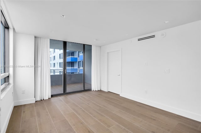 empty room featuring floor to ceiling windows and light wood-type flooring