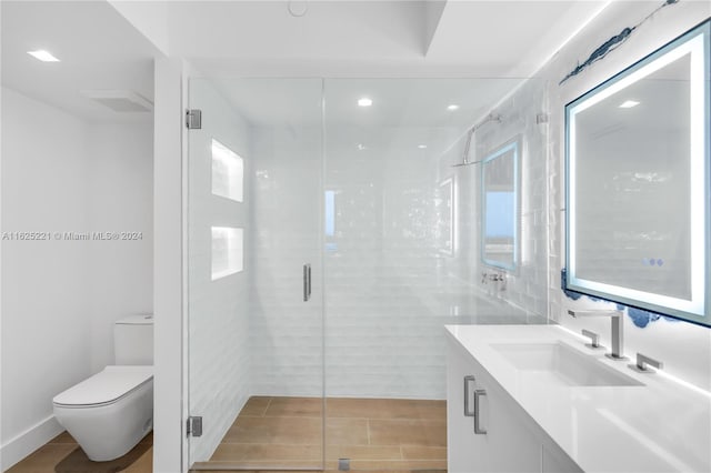 bathroom with a shower with door, tile walls, tile patterned floors, toilet, and vanity