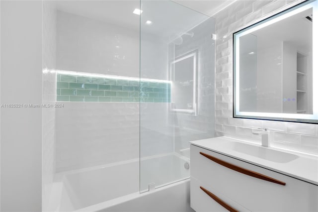 bathroom with vanity, combined bath / shower with glass door, tile walls, and tasteful backsplash