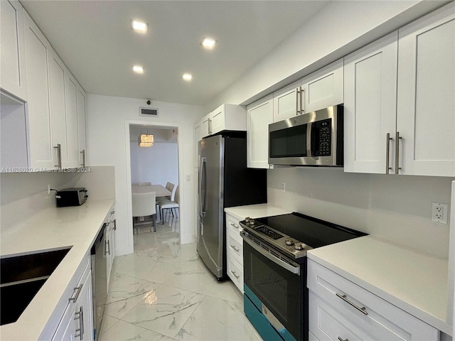 kitchen with white cabinetry, appliances with stainless steel finishes, sink, and pendant lighting