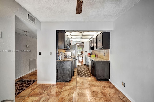 kitchen featuring light stone counters, sink, a textured ceiling, and decorative backsplash