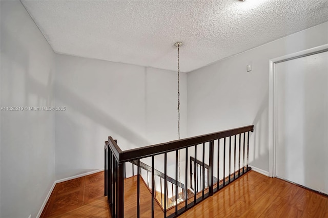 stairs featuring hardwood / wood-style floors and a textured ceiling