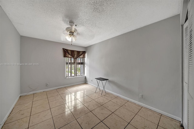 tiled empty room with ceiling fan and a textured ceiling