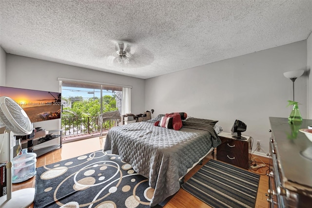 bedroom featuring ceiling fan, access to outside, a textured ceiling, and wood-type flooring