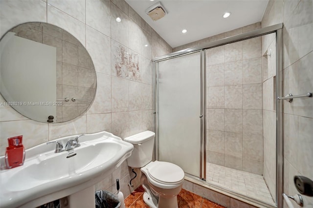 bathroom featuring tile patterned flooring, sink, tile walls, toilet, and a shower with shower door