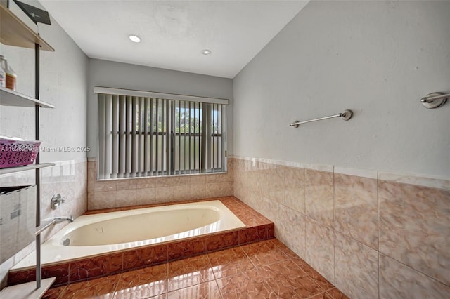 bathroom with tile walls, tiled bath, and tile patterned flooring