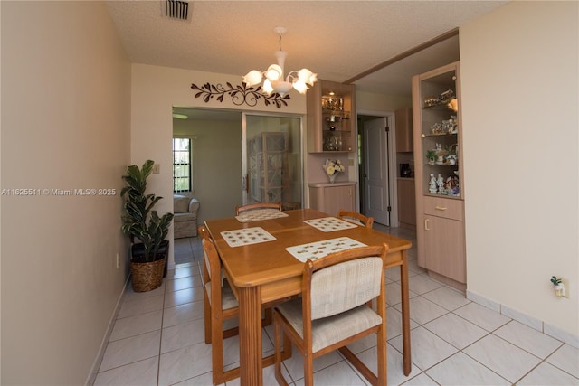 dining area featuring light tile patterned flooring, a notable chandelier, and a textured ceiling