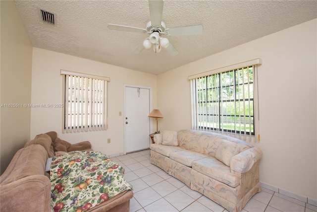 living room with ceiling fan, plenty of natural light, light tile patterned floors, and a textured ceiling