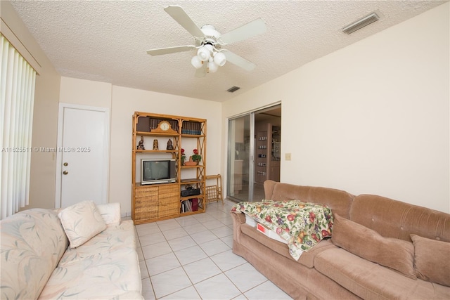 living room with ceiling fan, light tile patterned floors, and a textured ceiling