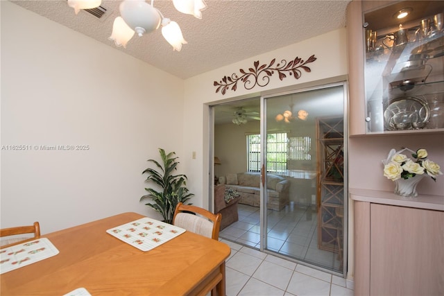 dining space with light tile patterned flooring, an inviting chandelier, and a textured ceiling