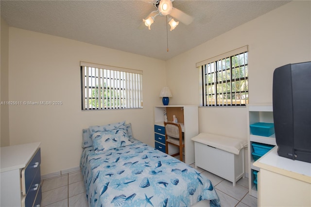 tiled bedroom with a textured ceiling and ceiling fan