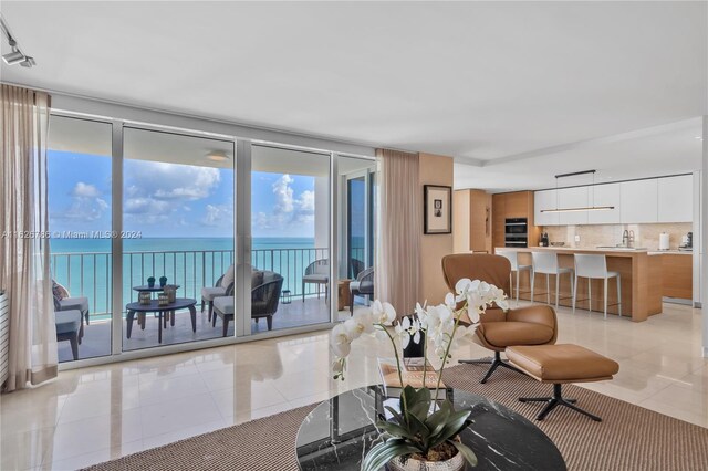 tiled living room featuring a water view and floor to ceiling windows