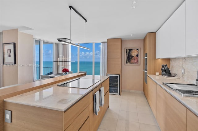 kitchen featuring sink, a water view, black electric cooktop, beverage cooler, and white cabinets