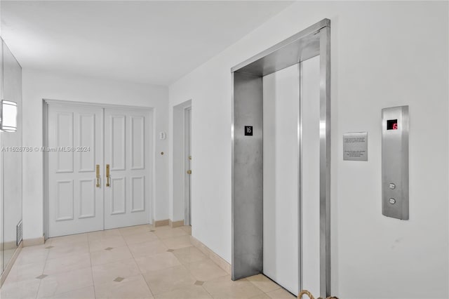 hallway with elevator and light tile patterned floors