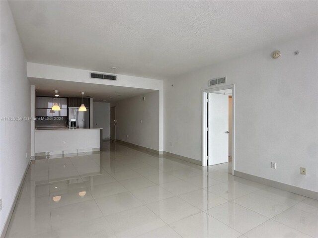 tiled empty room with a textured ceiling