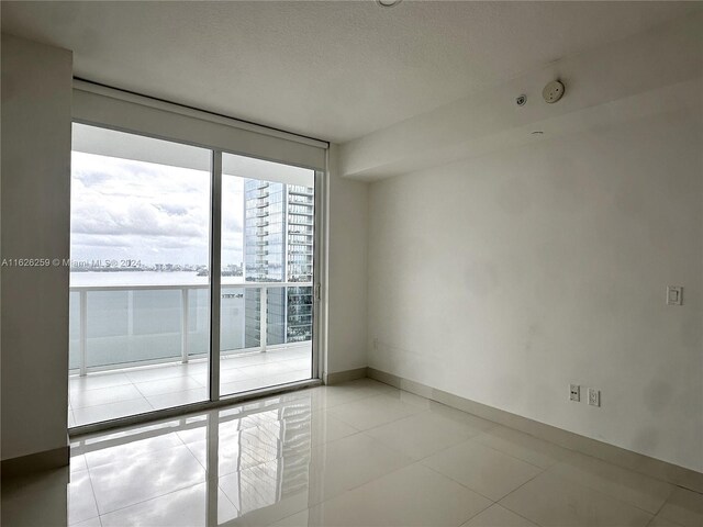 spare room with a wall of windows and light tile patterned flooring