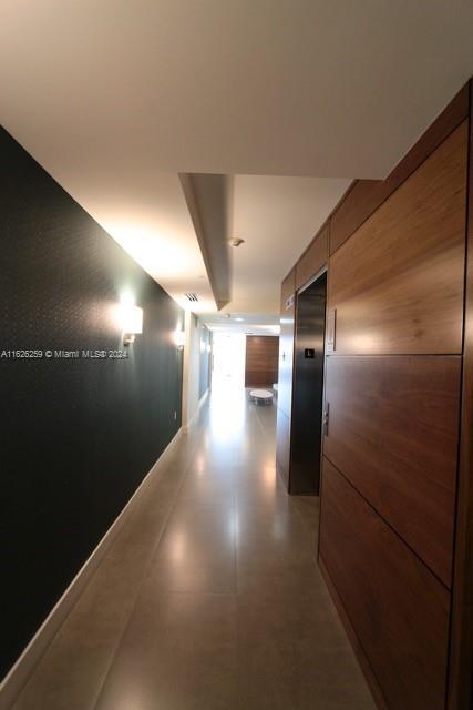 corridor featuring elevator and wood walls