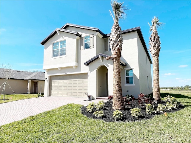 view of front facade featuring a front yard, decorative driveway, and stucco siding