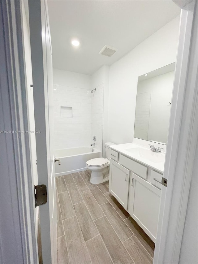 full bath with toilet, wood finish floors, vanity, visible vents, and shower / bathing tub combination