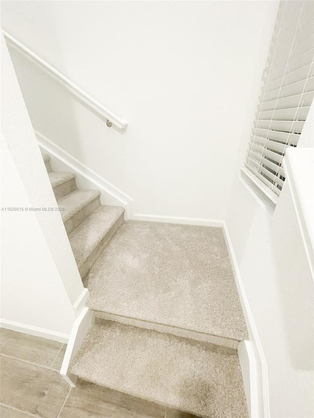 staircase featuring carpet and baseboards