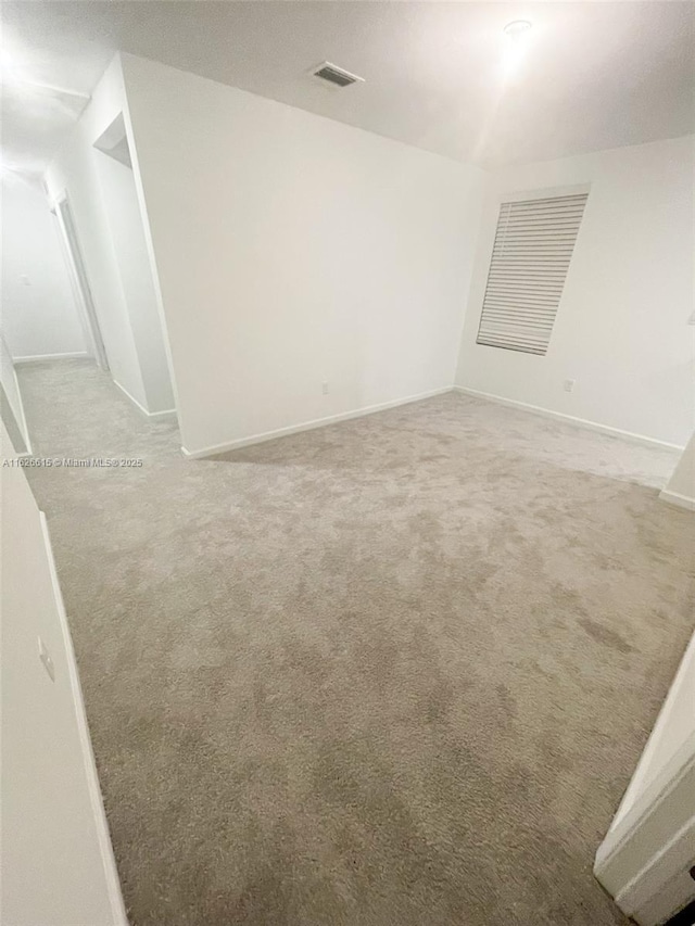 spare room featuring carpet floors, visible vents, and baseboards