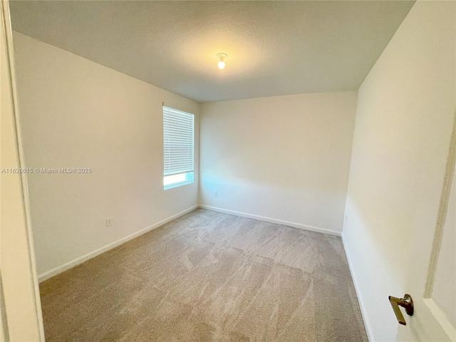 unfurnished room featuring baseboards and light colored carpet