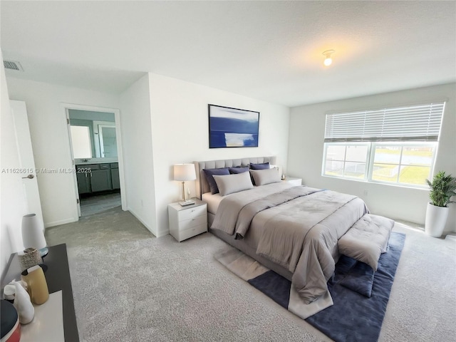 bedroom with carpet floors, visible vents, baseboards, and ensuite bathroom