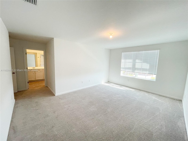 spare room featuring baseboards and light colored carpet