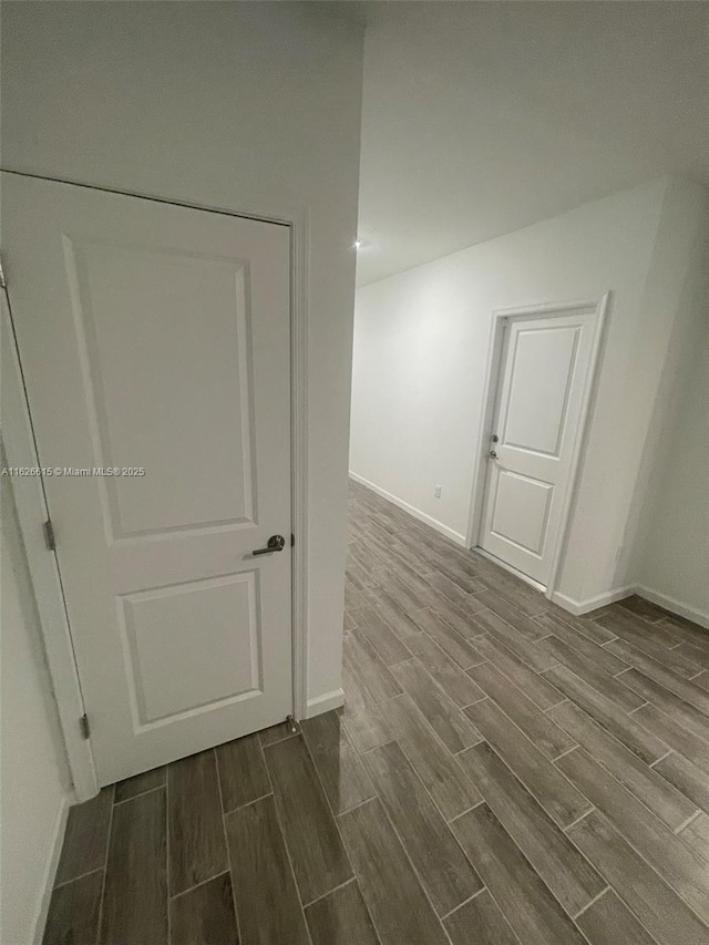 unfurnished room featuring baseboards and wood tiled floor