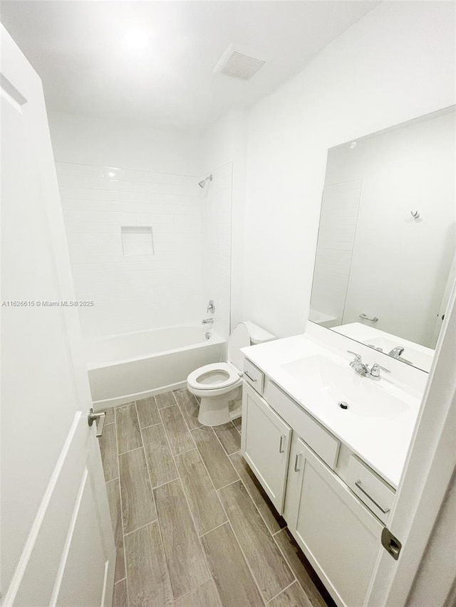 bathroom featuring toilet, vanity, tub / shower combination, and wood finish floors