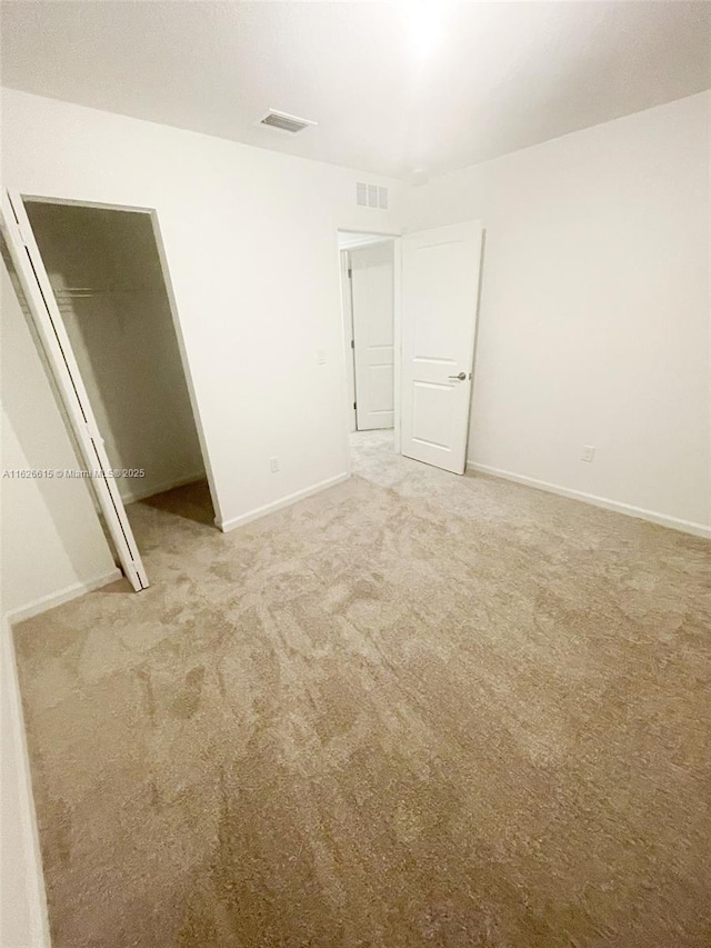 unfurnished bedroom featuring carpet floors, baseboards, visible vents, and a closet