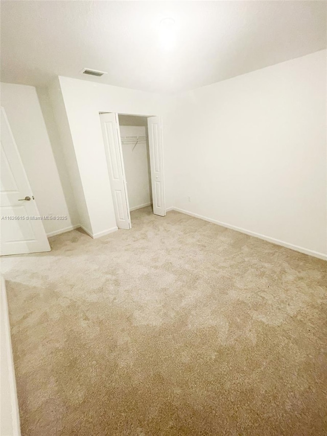 unfurnished bedroom with a closet, light carpet, visible vents, and baseboards