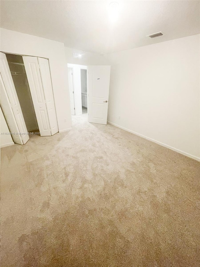 unfurnished bedroom with a closet, light carpet, and baseboards