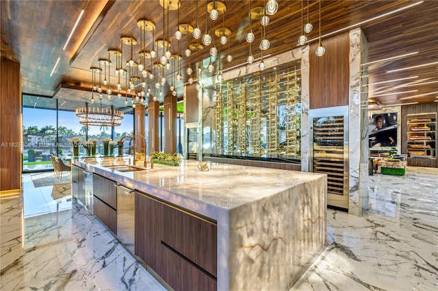 kitchen featuring light tile patterned flooring, hanging light fixtures, light stone counters, and an island with sink