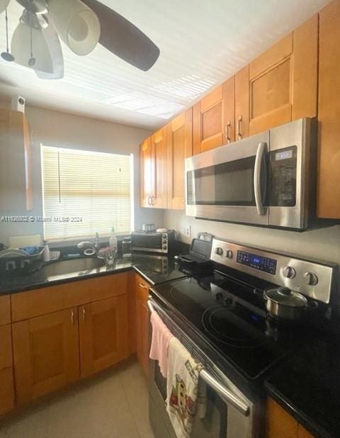 kitchen with sink, appliances with stainless steel finishes, light tile patterned flooring, and ceiling fan